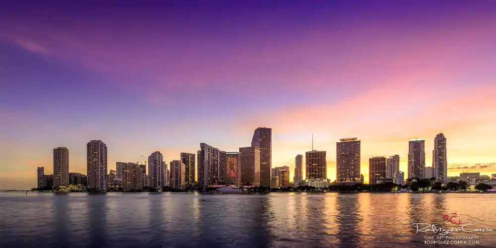 Miami skyline as viewed from offshore at sunset with pink and magenta colors over the sky.